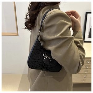 Détail d'un sac bandoulière noir texturé avec boucle métallique en forme de nœud argenté