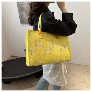 Gros plan du sac fourre-tout jaune avec texture logo matelassée et broderies ondulées