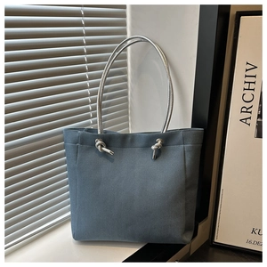 Detailed view of grey-blue denim tote bag with unique silver metallic rope handle