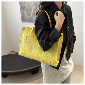 Détail du sac cabas jaune avec broderies colorées et texture de lettres en relief