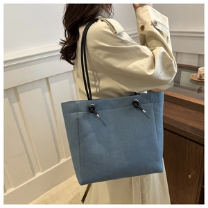 Detail of blue denim tote bag with drawstring knot and slim black shoulder strap
