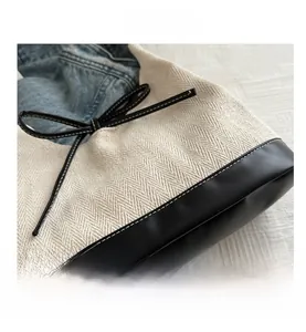 Detail of herringbone canvas tote featuring black leather contrast and bow decoration