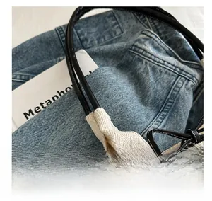 Detail view of woven texture fabric and fine leather stitching on minimalist tote bag