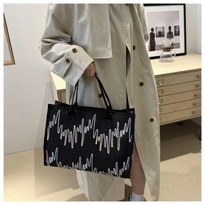Sac cabas noir chic avec broderie arc-en-ciel tenu par un mannequin en trench-coat
