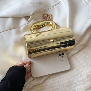 Elegant gold cylindrical acrylic clutch bag with a sleek metal handle and chain strap