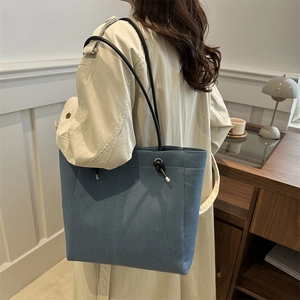 Minimalist denim tote bag with thin black shoulder straps and silver metal hardware