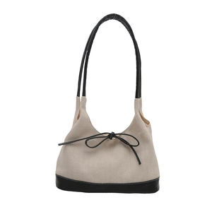 Minimalist canvas tote bag with black leather trim and bow detail in creamy white