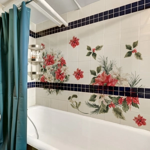 Close-up of Christmas wall stickers with red poinsettia and green leaves on bathroom tiles