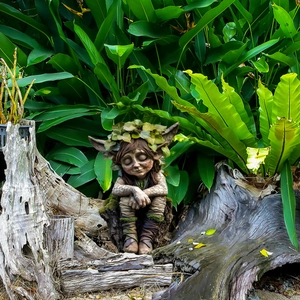 Creative tree elf garden stake ornament with leaf crown in a natural forest setting