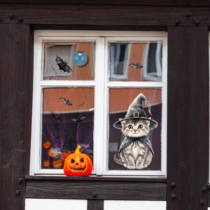 Detail von Halloween-Fensteraufklebern mit Katze im Hexenhut und Fledermäusen auf Glas