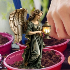 Garden fairy statue with warm glowing lantern and detailed wings in flower pot decor