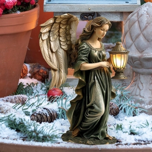 Fairy garden stake with golden wings and LED lantern in a winter landscape setting