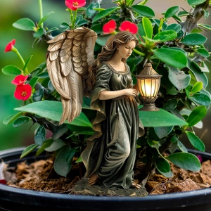 Detailed view of fairy garden statue with golden wings and glowing lantern in plants