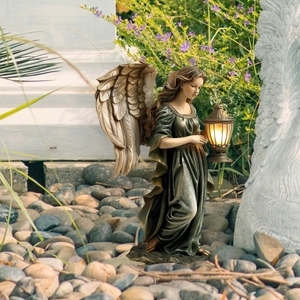Garden angel statue with solar lantern detail among lavender and stones