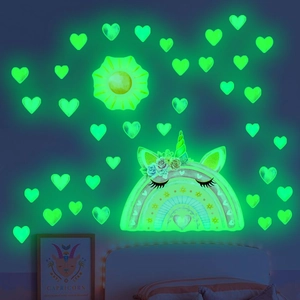 Luminous unicorn and rainbow wall decals with heart stickers glowing in a dark bedroom