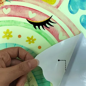 Close-up of peeling self-adhesive backing from a luminous rainbow heart wall sticker