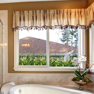 Detail of a beige and brown striped window valance with decorative tassels in a bathroom