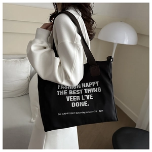 Détail du grand cabas en toile noire avec typographie blanche et anses marron