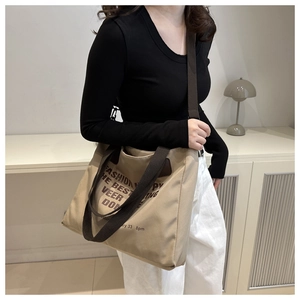 Detail of khaki canvas tote bag with fashion letter print and brown strap in cozy setting