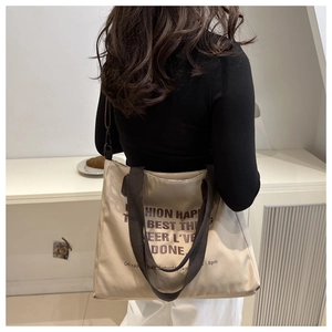 Beige canvas tote bag with brown straps and artistic text shown in a cozy lifestyle setting