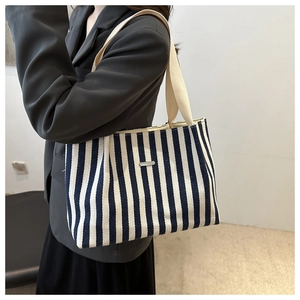 Détail du sac cabas en toile rayée marine avec larges bretelles et plaque métallique