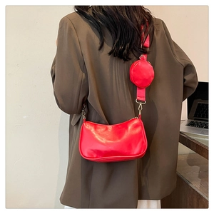 Detail of red crescent bag with wide strap and matching round coin purse on shoulder
