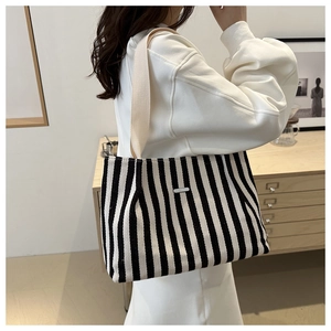 Détail du sac cabas en toile à rayures noires et blanches porté par un mannequin de côté