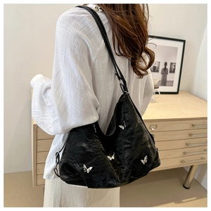 Detail of black Hobo tote bag with silver butterfly charms and textured pleated leather