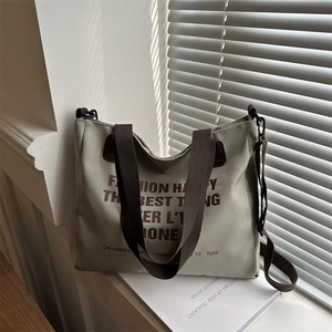 Sage green canvas tote bag with brown letter print and adjustable crossbody strap