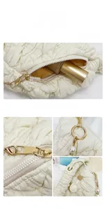 Detail of off-white quilted puffer bag featuring golden zipper and elegant pearl pendant
