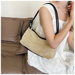 Detail of handwoven straw shoulder bag with black leather trim worn on a white lace dress