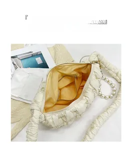 Detail view of the quilted bubble bag with yellow lining and large pearl chain decoration