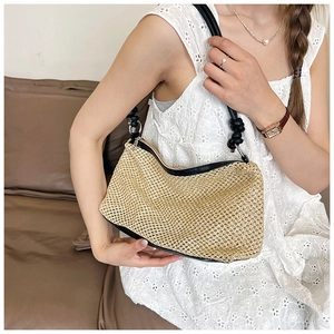 Detail of beige straw underarm bag with black leather knot strap and natural texture