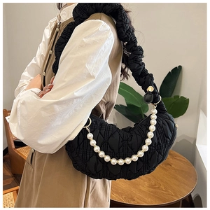 Close-up of black quilted half-moon bag featuring pearl chain and pleated shoulder strap