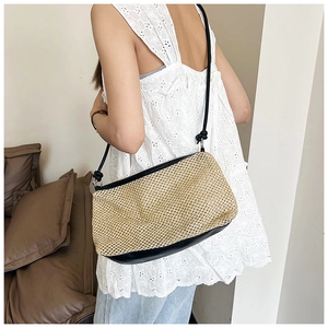 Detail of the straw shoulder bag with black PU leather trim and knotted strap design