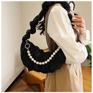 Detail of black quilted cloud bag featuring pearl chain strap and ruffled handle