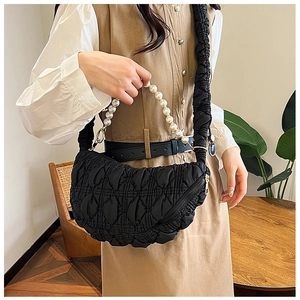 Detail of black crescent cloud bag featuring quilted texture and faux pearl handle