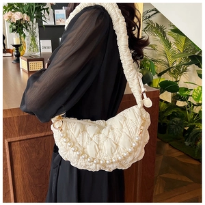 Detail of white pleated cloud bag with elegant pearl chain strap and soft leather texture