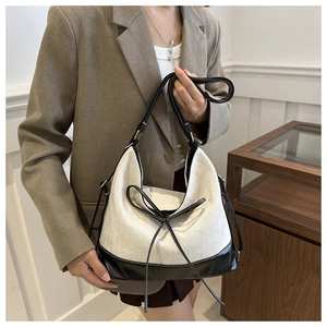 Detail of large canvas tote bag with contrast leather strap and elegant bow detail