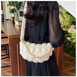 Detail of quilted cloud bag with pearl chain and pleated strap on a model shoulder