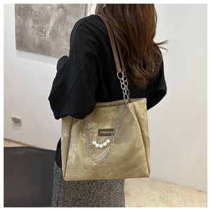 Detail of olive green tote bag featuring silver chain and white pearl accents on textured leather