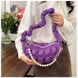 Detail of purple quilted cloud bag with ruched handle and pearl chain accessory