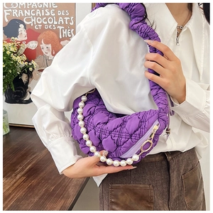 Macro view of purple quilted crescent bag featuring pearl handle and pleated strap detail