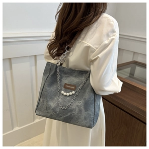 Detail of grey canvas tote with brown leather patch and silver chain with pearls