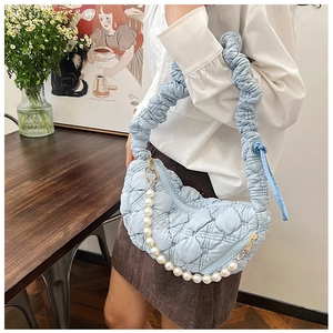 Detail of light blue quilted crescent bag with scrunched handle and pearl chain