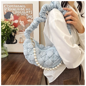 Close-up of light blue quilted shoulder bag with pearl chain and ruched handle detail