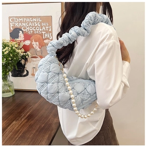 Detail of light blue quilted bag featuring cloud-like pleated strap and pearl chain decoration