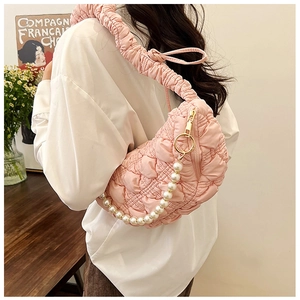 Detail of pink quilted bubble bag featuring a ruffled strap and large pearl chain charm