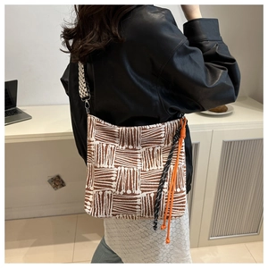 Detail of canvas tote bag with brown geometric patterns and braided wide shoulder strap