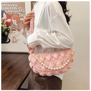 Detail of pink quilted puff bag featuring a pearl charm and pleated shoulder strap